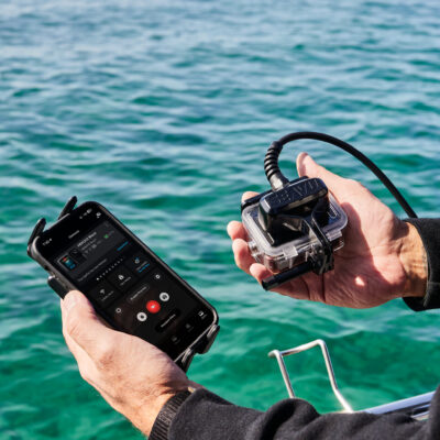 手持运动相机和手机的人使用 Seavu Seeker 连接，接收器和发射器之间有电缆连接