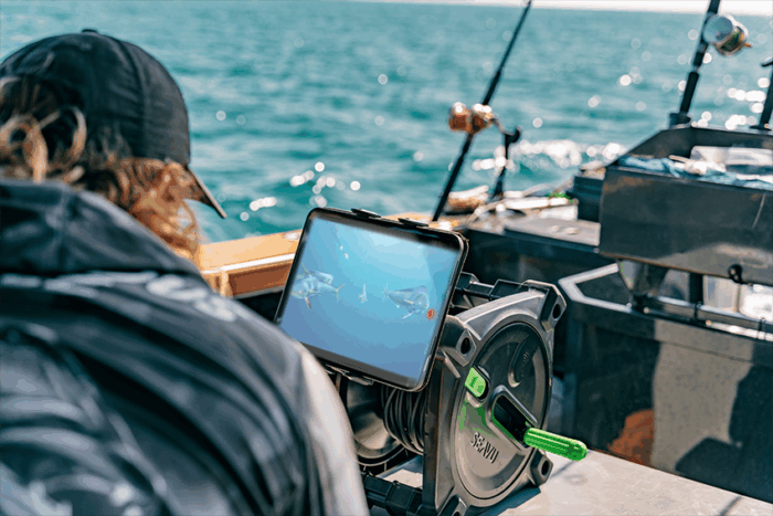 船上的一名男子通过安装在 Seavu Explorer Reel 上的平板电脑观看水下鲯鳅鱼的实时直播